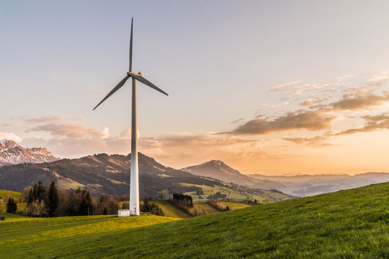 Wind turbine amid rolling hills at sunset